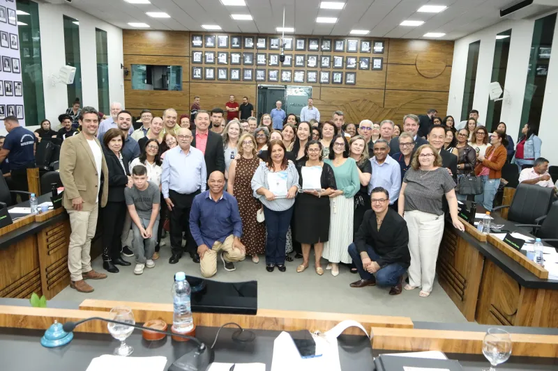 Ganhadora do título de Professora do Ano, Neusa e ganhadora do título de Educadora do Ano, Lúcia Cristina com participantes na cerimônia de homenagem